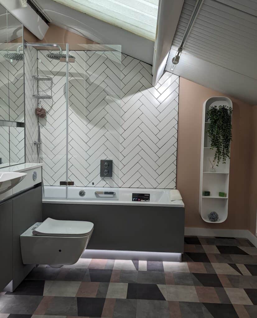 A bathroom with pink painted walls, white tiling and a combination of grey and mirrored furniture.