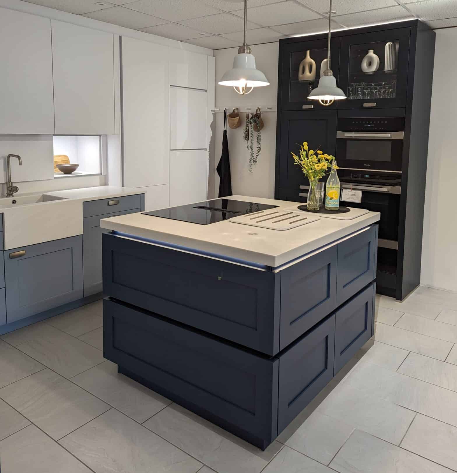 A photo of a modern shaker kitchen with an island with a induction hob and Corian white worktops.