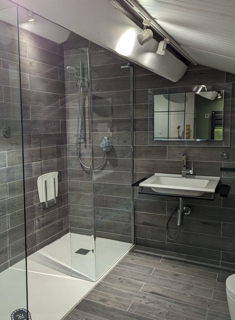 Bathroom display with solidsoft shower tray, wood effect tiles and chrome accents